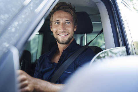 Lächelnder junger Mann im Auto, lizenzfreies Stockfoto