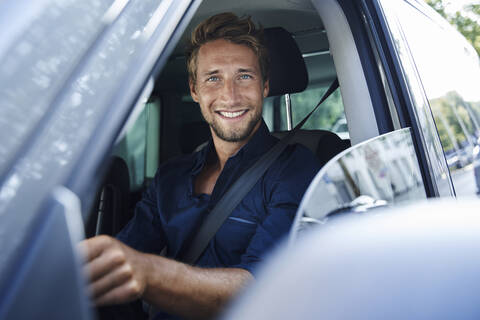 Porträt eines lächelnden jungen Mannes im Auto, lizenzfreies Stockfoto