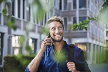 Smiling young businessman on the phone in the city - PNEF02111