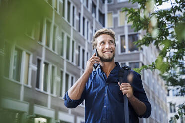 Smiling young businessman on the phone in the city - PNEF02112