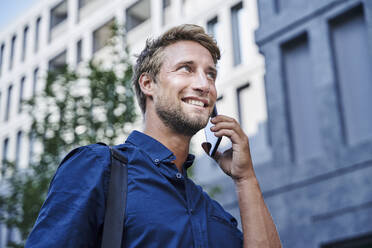 Smiling young businessman on the phone in the city - PNEF02116