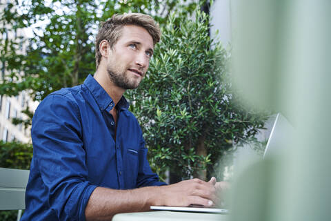 Young businessman using laptop at an outdoor cafe in the city stock photo