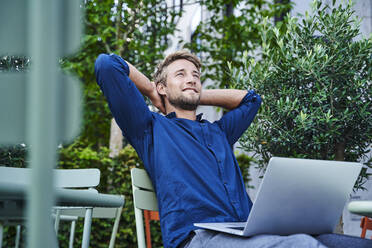 Young businessman with laptop at an outdoor cafe in the city having a break - PNEF02121