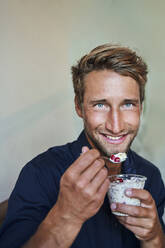 Portrait of smiling young man eating muesli - PNEF02141