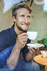 Portrait of young man drinking coffee in a cafe - PNEF02142