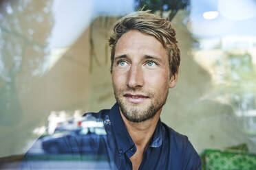 Portrait of young man behind windowpane - PNEF02145