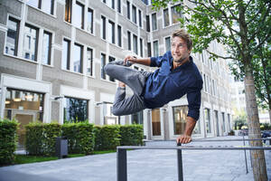 Junger Mann springt über ein Geländer in der Stadt - PNEF02164