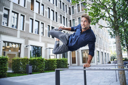 Young man jumping over railing in the city - PNEF02164