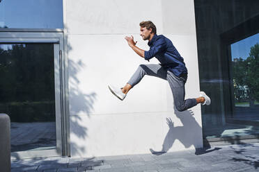 Young businessman jumping mid-air in the city - PNEF02165