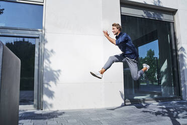 Young businessman jumping mid-air in the city - PNEF02166