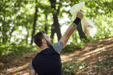 Sportlicher Mann mit Müllsack im Wald - ZEDF02624