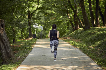 Rückansicht einer sportlichen jungen Frau beim Laufen auf einem Waldweg - ZEDF02628