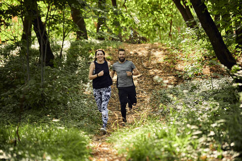 Sportliches Paar beim Laufen auf einem Waldweg - ZEDF02634