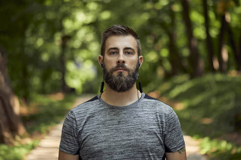 Porträt eines sportlichen Mannes mit Kopfhörern im Wald - ZEDF02640