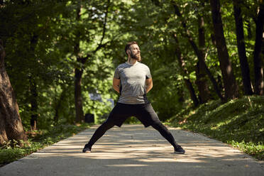 Sportlicher Mann beim Stretching auf einem Waldweg - ZEDF02644