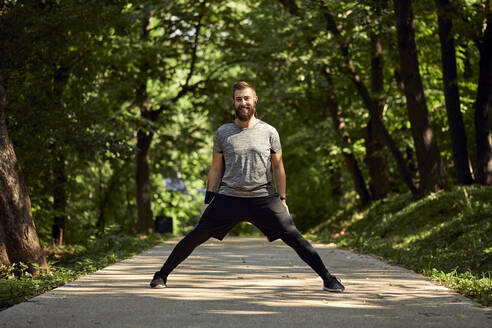 Sportlicher Mann beim Stretching auf einem Waldweg - ZEDF02645