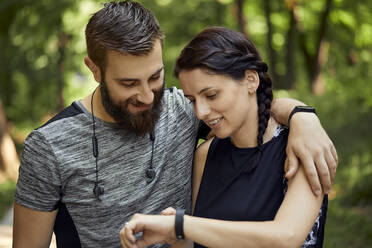 Glückliches sportliches Paar, das seine Smartwatch überprüft - ZEDF02651