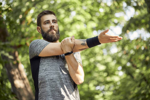 Sportlicher Mann beim Dehnen in der Natur, lizenzfreies Stockfoto