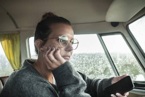 Woman with smartphone in a van looking sideways - NAF00128