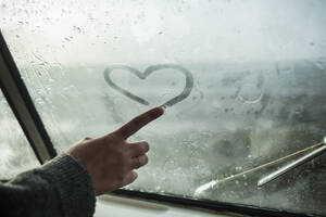 Der Finger einer Frau zeichnet ein Herz auf das Fenster eines Lieferwagens - NAF00129