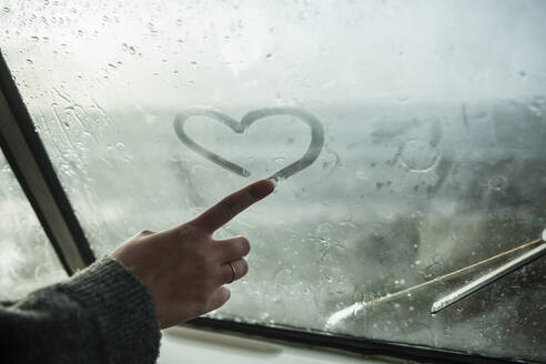 Woman's finger drawing a heart on the window of a van - NAF00129