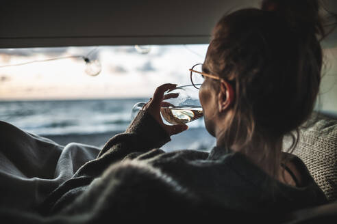 Young woman with glass of white wine in van - NAF00138