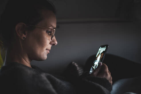 Woman looking at her smartphone during video chat, in a van - NAF00139