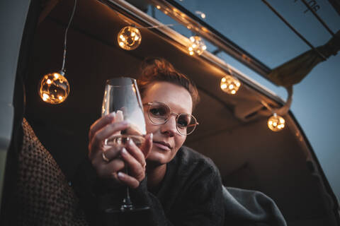 Porträt einer Frau mit einem Glas Weißwein in einem Van am Abend, lizenzfreies Stockfoto