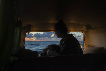 Woman in a van looking sideways at sunset - NAF00145