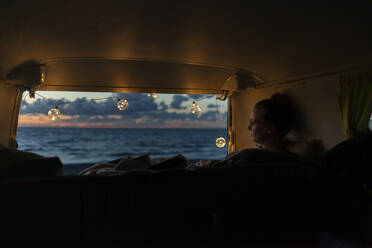 Woman in a van looking sideways at sunset - NAF00146