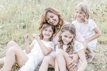 Happy mother with three triplet daughters in a field - STBF00434