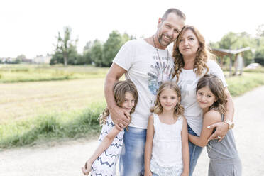 Happy parents with three triplet sisters outdoors - STBF00439