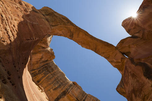 Sandstone rock arch with sunburst against blue sky in Colorado - CAVF64820