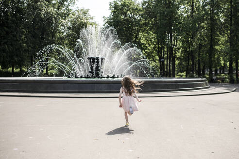 Kleines Mädchen läuft auf einen Brunnen zu - EYAF00539