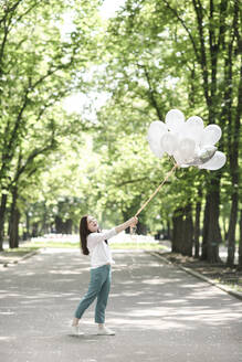 Glückliche Frau mit Luftballons in einem Park - EYAF00546
