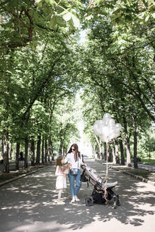 Mutter mit ihren beiden Kindern und Luftballons im Park - EYAF00547