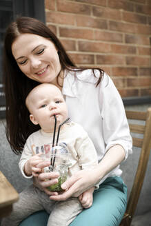 Lächelnde Mutter mit ihrem kleinen Jungen, der Limonade trinkt - EYAF00548