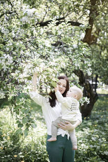 Mutter mit ihrem kleinen Jungen an einem Baum im Park - EYAF00557