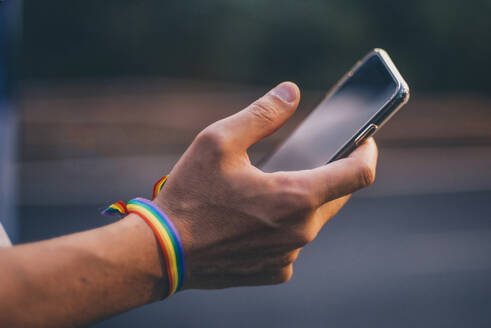 Hände eines Mannes mit Pusera-Gay-Flagge, der ein Smartphone hält - CJMF00070