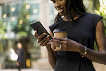 Businesswoman using smartphone in the city - MAUF02919