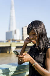 Businesswoman using smartphone in the city - MAUF02938