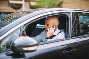 Geschäftsmann, der ein Fahrzeug fährt und ein Smartphone benutzt - CJMF00078