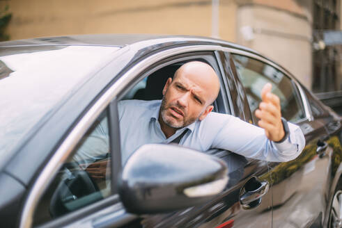 Businessman driving car and looking angry - CJMF00079