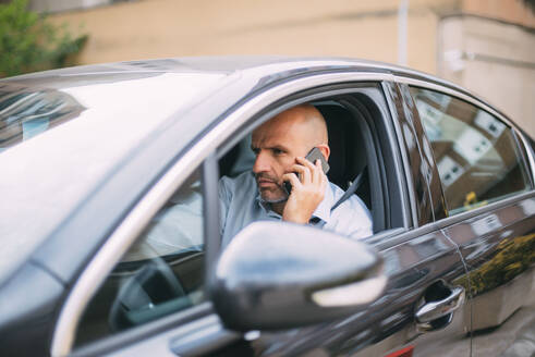 Geschäftsmann, der ein Fahrzeug fährt und ein Smartphone benutzt - CJMF00080