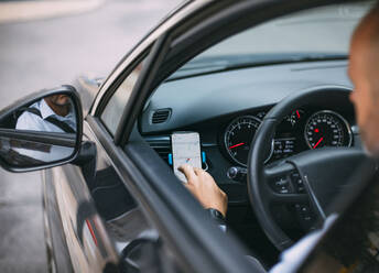 Geschäftsmann, der ein Fahrzeug fährt und ein Smartphone benutzt - CJMF00081