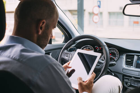 Geschäftsmann, der ein Fahrzeug fährt und ein Tablet benutzt - CJMF00082