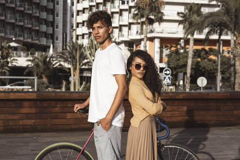 Cooles Paar mit Fahrrad in der Stadt, Rücken an Rücken stehend - RCPF00019