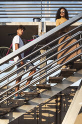 Young couple climbing stairs, carrying bicycle - RCPF00025