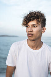 Porträt eines jungen Mannes mit lockigem Haar am Meer - RCPF00033