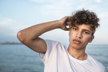 Porträt eines jungen Mannes mit lockigem Haar am Meer - RCPF00034